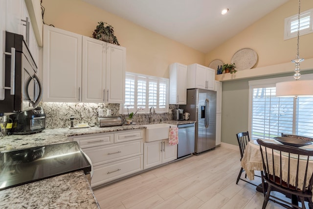 kitchen with appliances with stainless steel finishes, white cabinetry, hanging light fixtures, and plenty of natural light