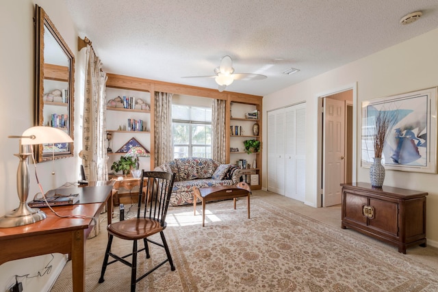 interior space featuring ceiling fan, a textured ceiling, and light colored carpet