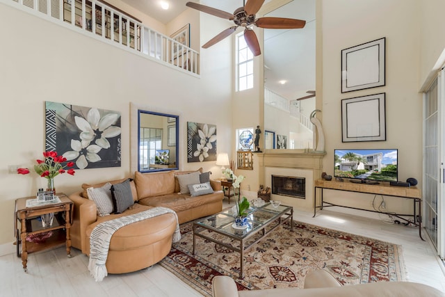 living room featuring a towering ceiling, ceiling fan, and light hardwood / wood-style floors