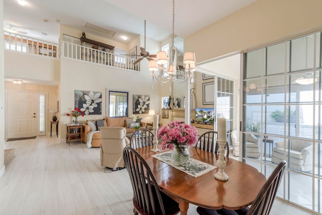 dining room with a wealth of natural light, a towering ceiling, light hardwood / wood-style floors, and ceiling fan