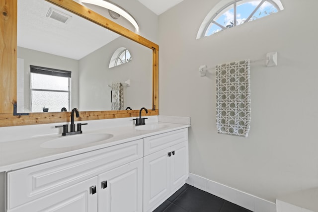 bathroom featuring vanity, vaulted ceiling, a wealth of natural light, and tile patterned flooring