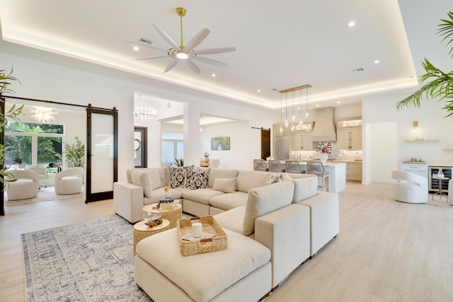 living room featuring light hardwood / wood-style floors, a barn door, ceiling fan, and wine cooler