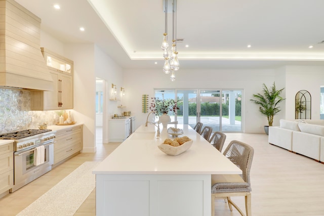 kitchen featuring a kitchen breakfast bar, custom range hood, high end range, and a kitchen island with sink