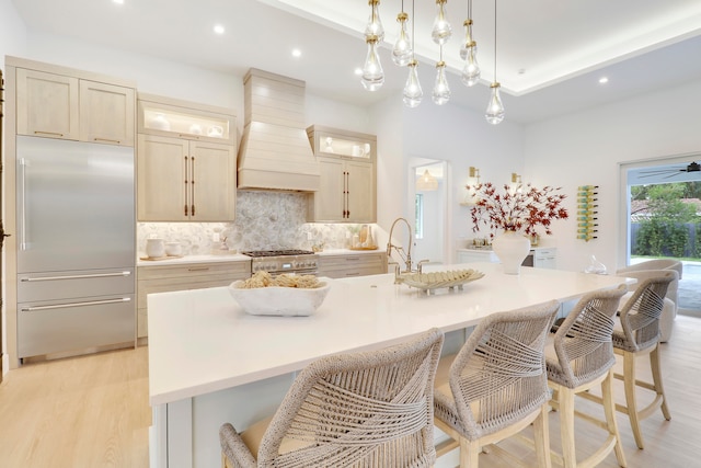 kitchen with a large island, a breakfast bar area, premium range hood, and stainless steel appliances