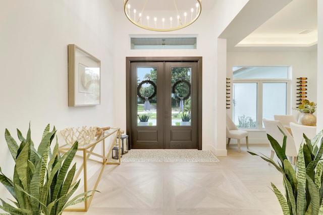 entrance foyer featuring french doors, plenty of natural light, and light parquet floors