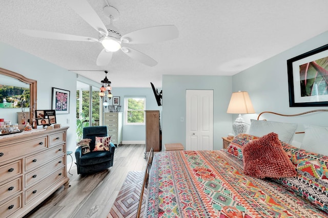 bedroom featuring a closet, ceiling fan, light hardwood / wood-style flooring, and a textured ceiling