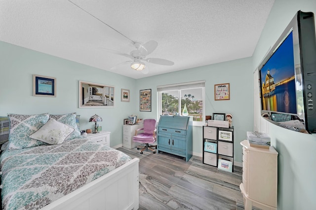 bedroom with ceiling fan, light wood-type flooring, and a textured ceiling