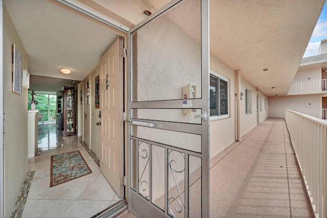 hall with light tile patterned flooring and a textured ceiling