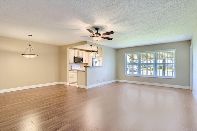 unfurnished living room featuring light wood-type flooring, ceiling fan, and a textured ceiling