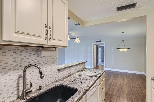 kitchen featuring light stone counters, dark hardwood / wood-style floors, tasteful backsplash, dishwasher, and a textured ceiling