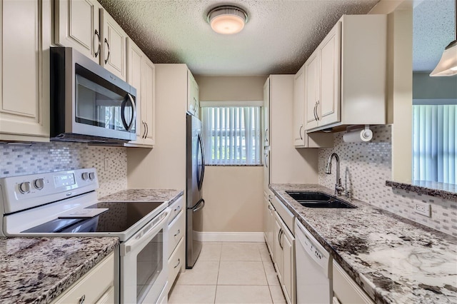 kitchen with appliances with stainless steel finishes, sink, tasteful backsplash, and white cabinetry