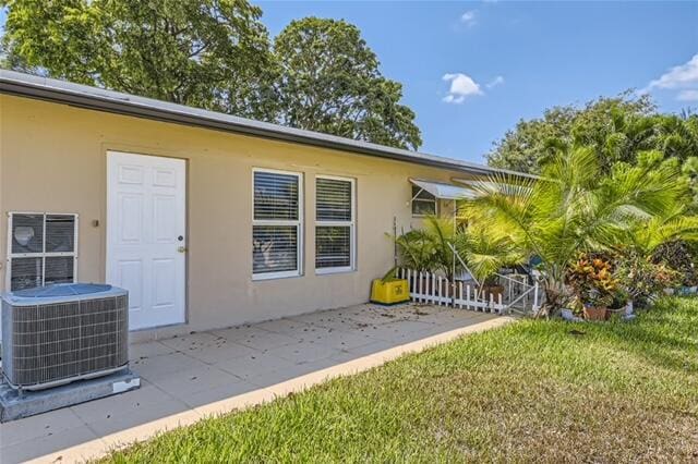 entrance to property with a yard and central AC unit