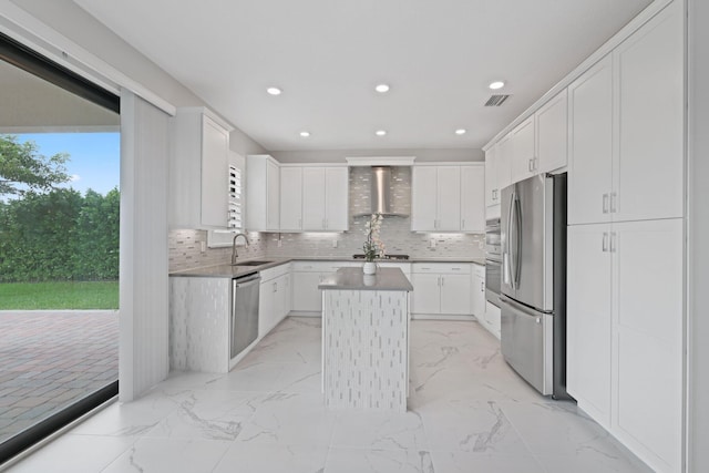 kitchen with a center island, wall chimney range hood, white cabinetry, and appliances with stainless steel finishes