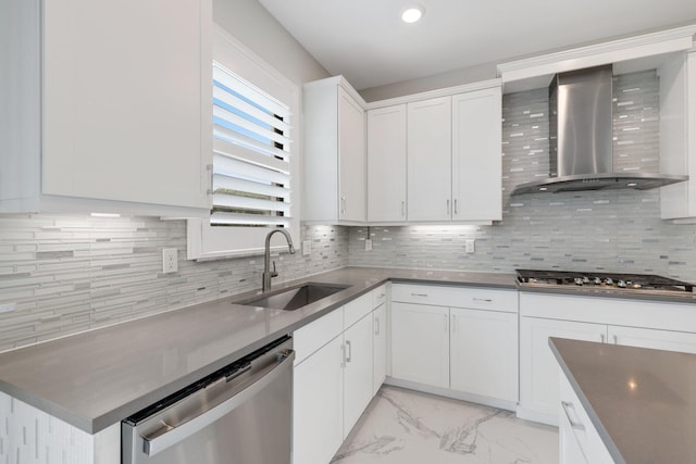 kitchen featuring wall chimney range hood, sink, decorative backsplash, white cabinetry, and stainless steel appliances