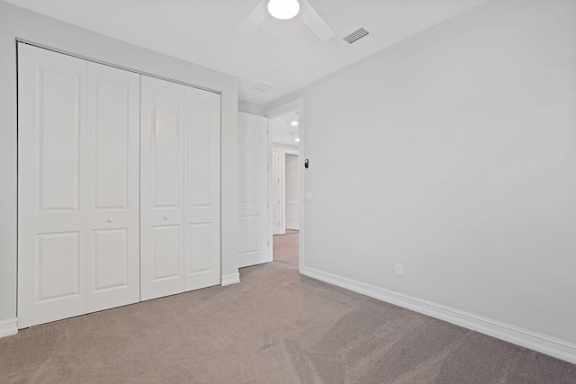 unfurnished bedroom with ceiling fan, light carpet, and a closet