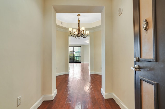 hall featuring dark hardwood / wood-style floors, an inviting chandelier, and ornamental molding