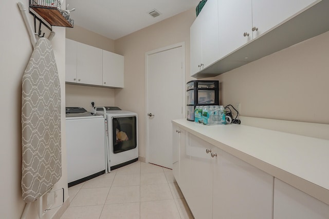 clothes washing area with cabinets, light tile patterned floors, and washing machine and dryer