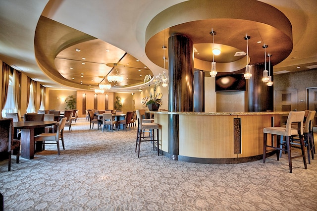 bar featuring carpet flooring, a tray ceiling, hanging light fixtures, and an inviting chandelier