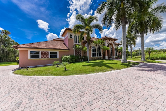 mediterranean / spanish home with stucco siding, a front yard, and a tile roof