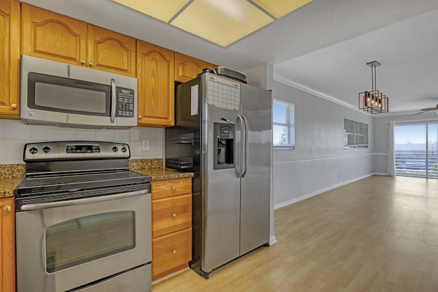 kitchen with light wood-type flooring, crown molding, a wealth of natural light, and stainless steel appliances