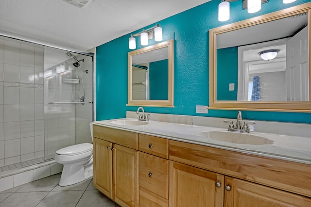 bathroom with vanity, tile patterned floors, a shower with shower door, toilet, and a textured ceiling