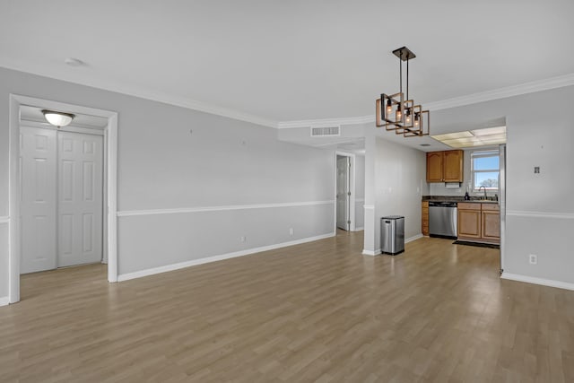 unfurnished living room with sink, light wood-type flooring, a chandelier, and ornamental molding