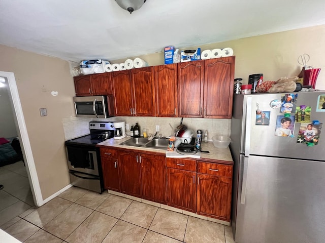 kitchen with light tile patterned floors, sink, stainless steel appliances, and backsplash