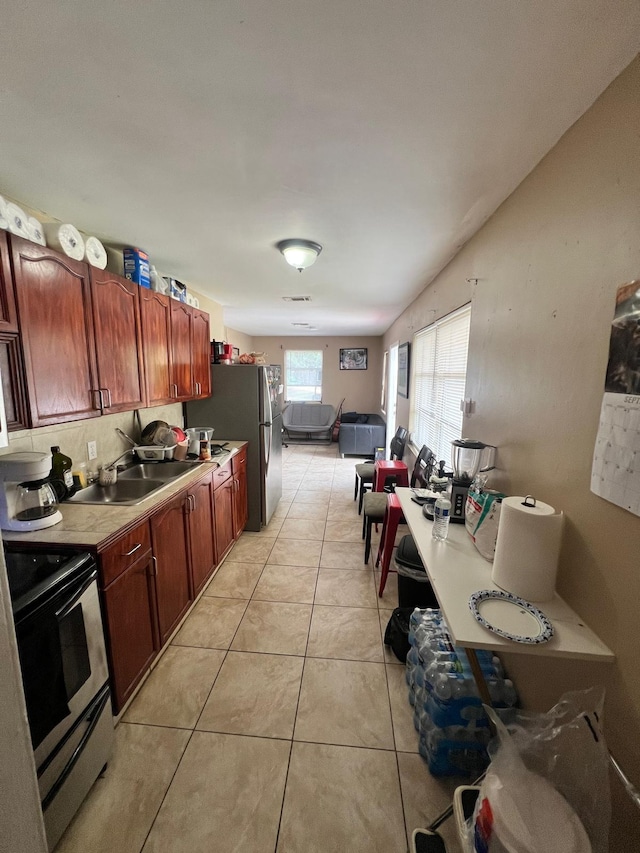 kitchen with stainless steel fridge, sink, light tile patterned floors, and black electric range