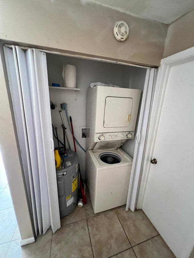 laundry area with stacked washer / dryer and light tile patterned floors