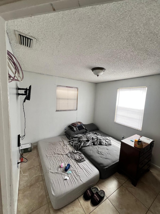 tiled bedroom featuring a textured ceiling