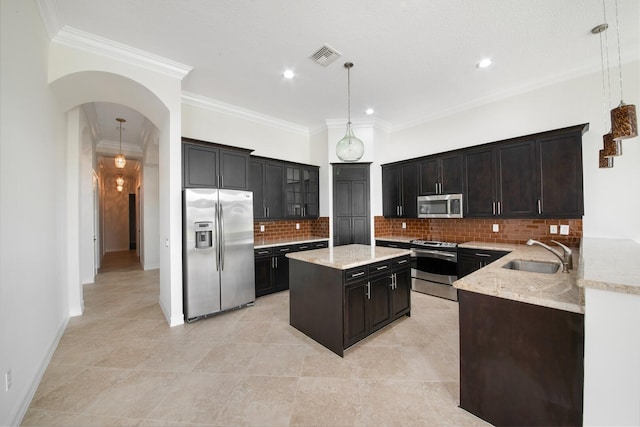 kitchen with decorative backsplash, stainless steel appliances, sink, crown molding, and hanging light fixtures