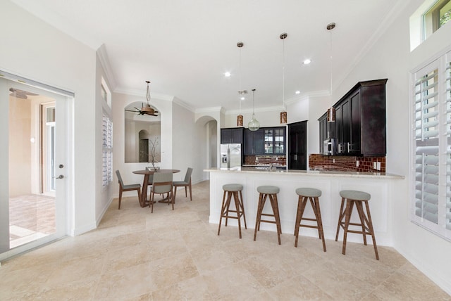 kitchen featuring ceiling fan, hanging light fixtures, kitchen peninsula, backsplash, and appliances with stainless steel finishes