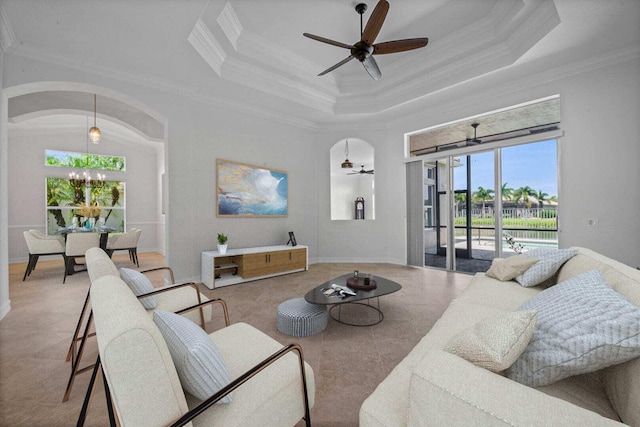 living room with a raised ceiling, ceiling fan with notable chandelier, and crown molding