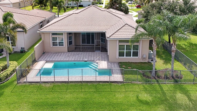 back of property featuring a fenced in pool, a patio area, and a lawn