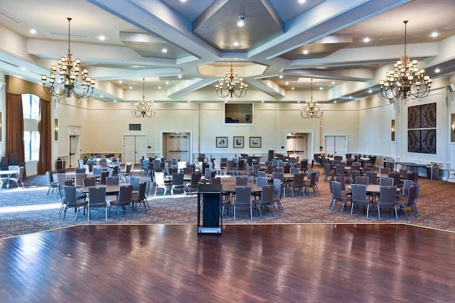 dining space with hardwood / wood-style flooring, beamed ceiling, and a towering ceiling