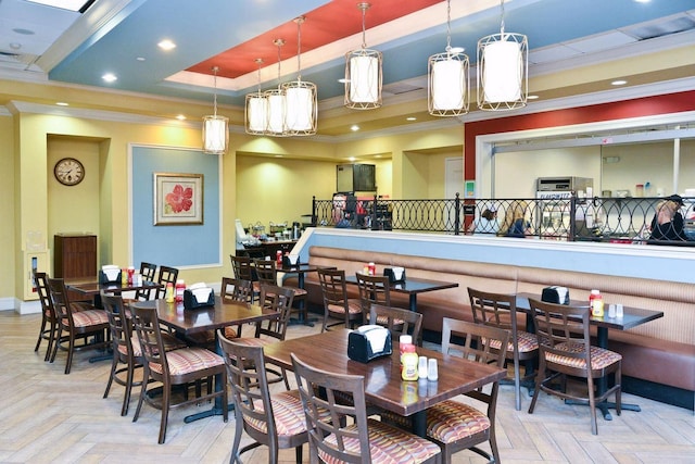 dining area with a raised ceiling, crown molding, and light parquet floors