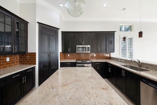 kitchen with light stone countertops, sink, pendant lighting, appliances with stainless steel finishes, and backsplash