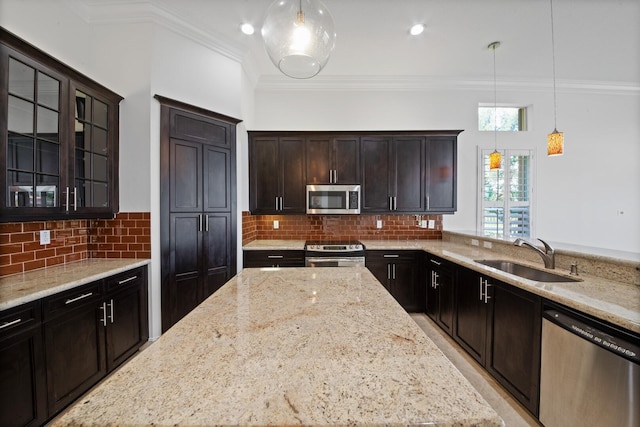 kitchen with light stone countertops, appliances with stainless steel finishes, hanging light fixtures, and sink