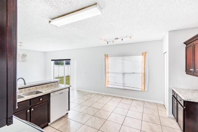 kitchen with dishwasher, sink, light tile patterned floors, and a textured ceiling