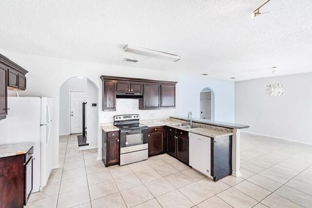 kitchen with kitchen peninsula, dark brown cabinetry, light tile patterned floors, a textured ceiling, and white appliances