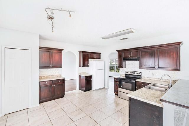 kitchen featuring white refrigerator, sink, electric range, rail lighting, and light tile patterned floors