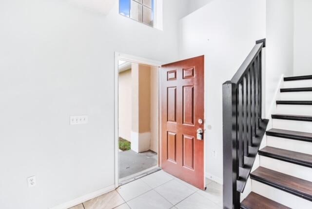 foyer entrance with a towering ceiling and light tile patterned floors