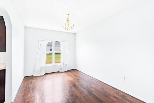 empty room featuring a chandelier and hardwood / wood-style floors