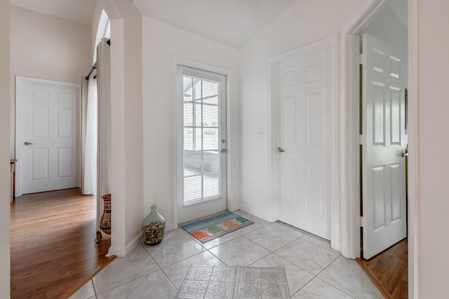 doorway with light hardwood / wood-style floors, lofted ceiling, and a barn door