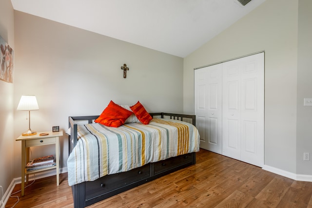 bedroom featuring a closet, wood-type flooring, and lofted ceiling