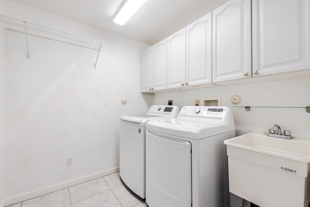 clothes washing area with light tile patterned flooring, cabinets, sink, and washing machine and clothes dryer