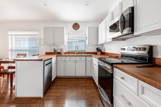 kitchen with dark hardwood / wood-style flooring, white cabinetry, stainless steel appliances, and butcher block countertops