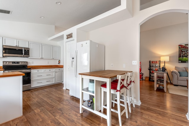 kitchen with white cabinets, stainless steel appliances, dark wood-type flooring, and butcher block countertops