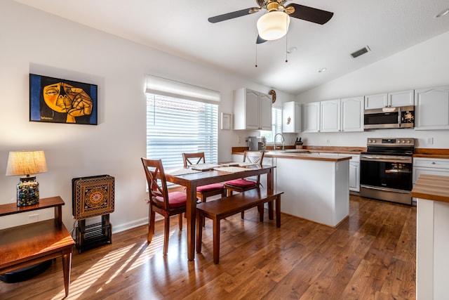 kitchen with dark wood-type flooring, stainless steel appliances, vaulted ceiling, white cabinetry, and ceiling fan