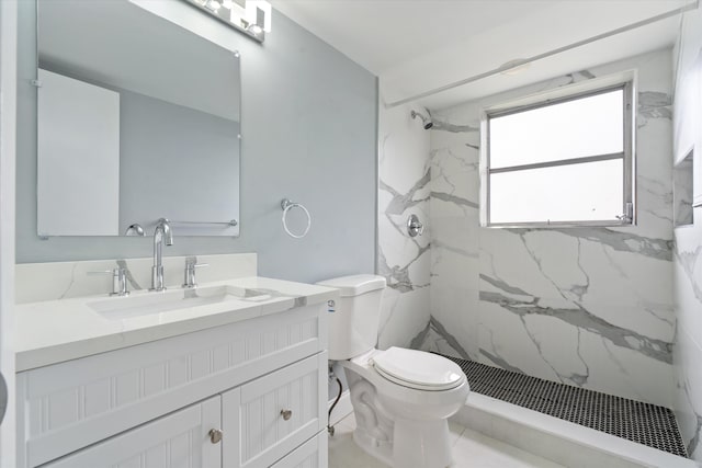 bathroom with tiled shower, vanity, and toilet